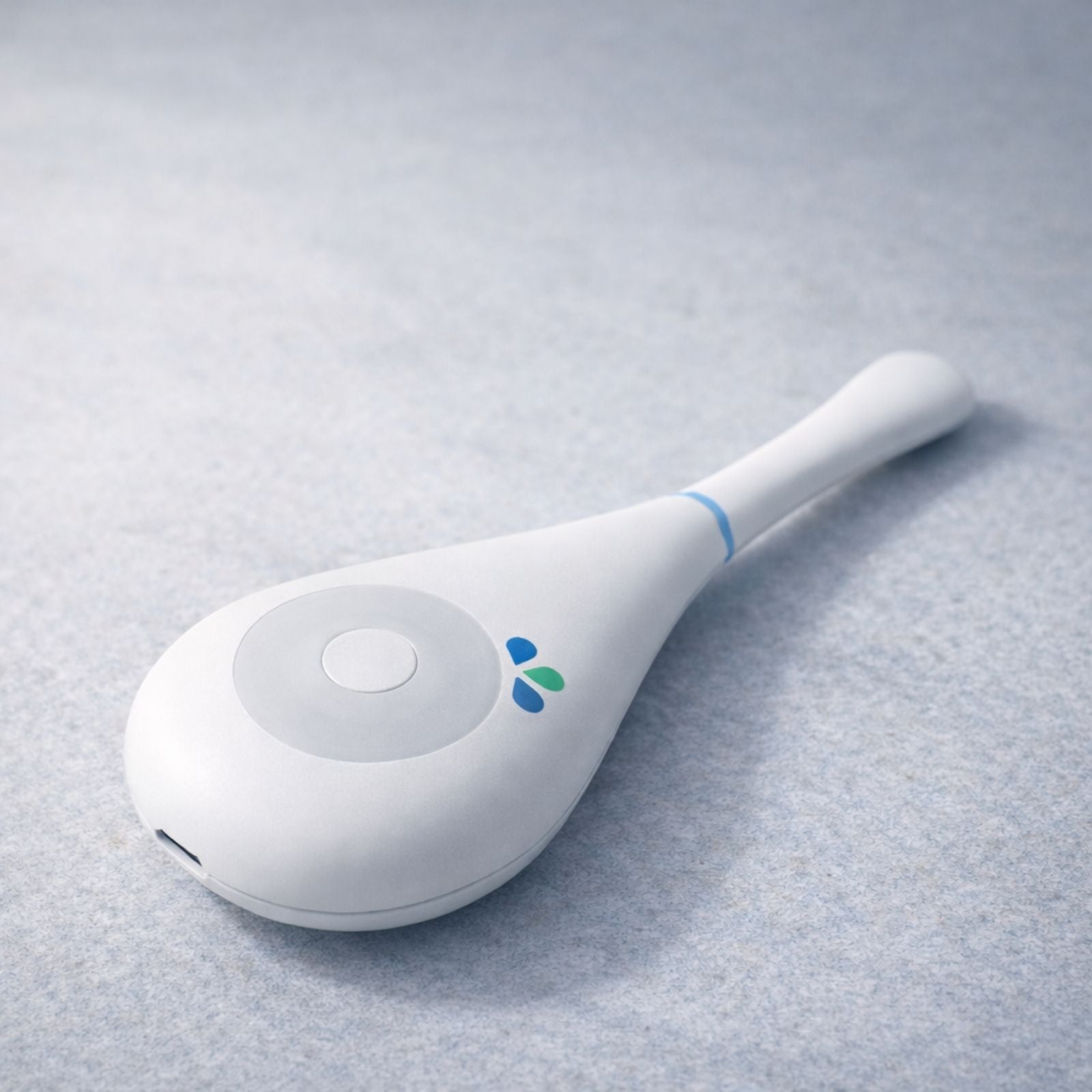 Daysy fertility tracker on grey stone surface showing full device profile, blue and green LED indicators and USB charging port