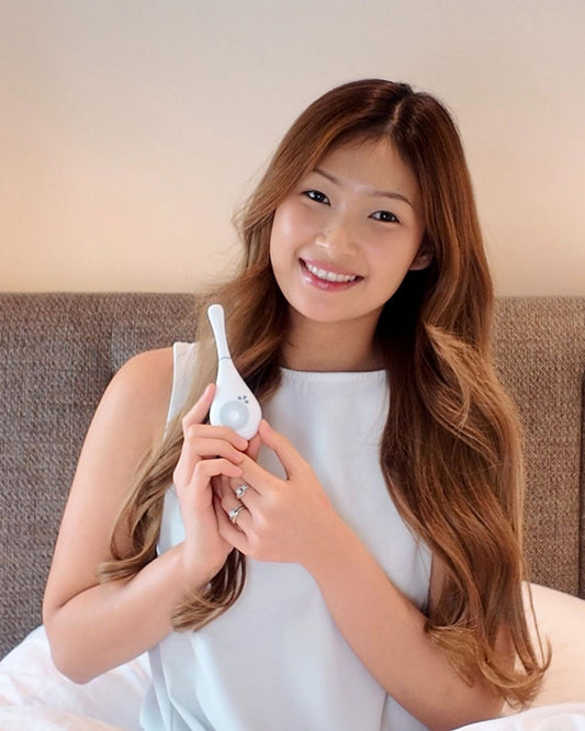 Woman holding Daysy fertility tracker in a bedroom setting